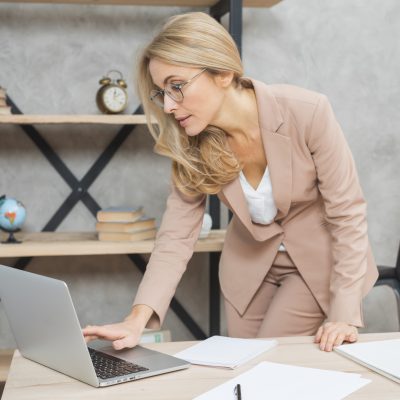 businesswoman-standing-workplace-using-laptop